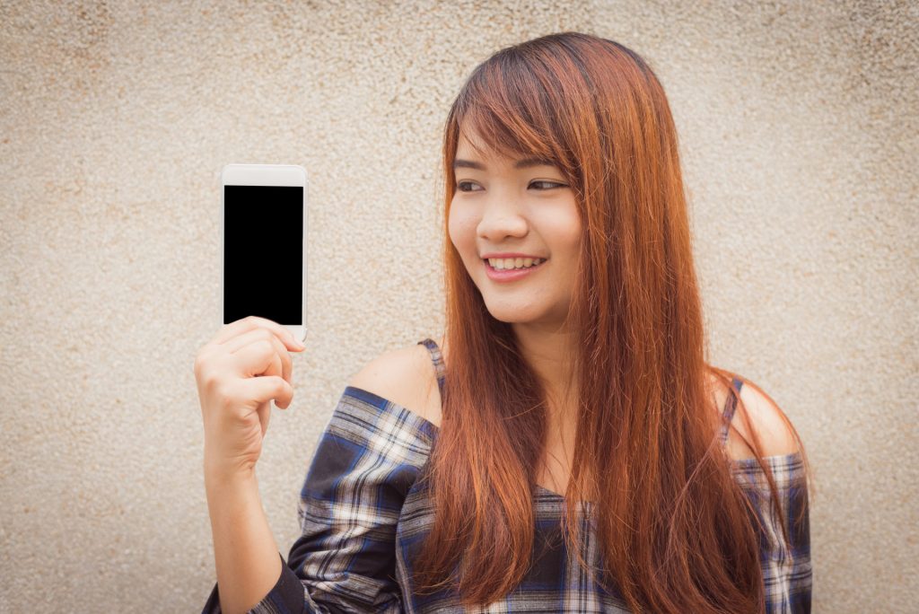Jeune femme qui préfère acheter éco-responsable son téléphone portable reconditionné